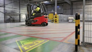 Heineken warehouse with E80 electric forklift truck and warning symbol on the hall floor