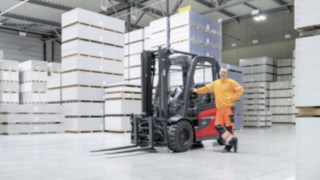A man leaning against a forklift truck in a warehouse